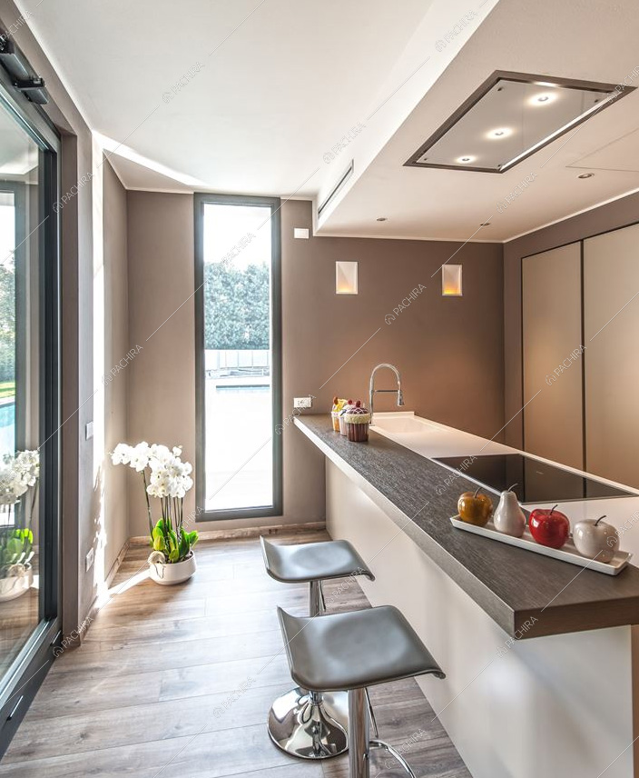 Cucina a penisola e vetrate in questa villa moderna in Provincia di Brescia