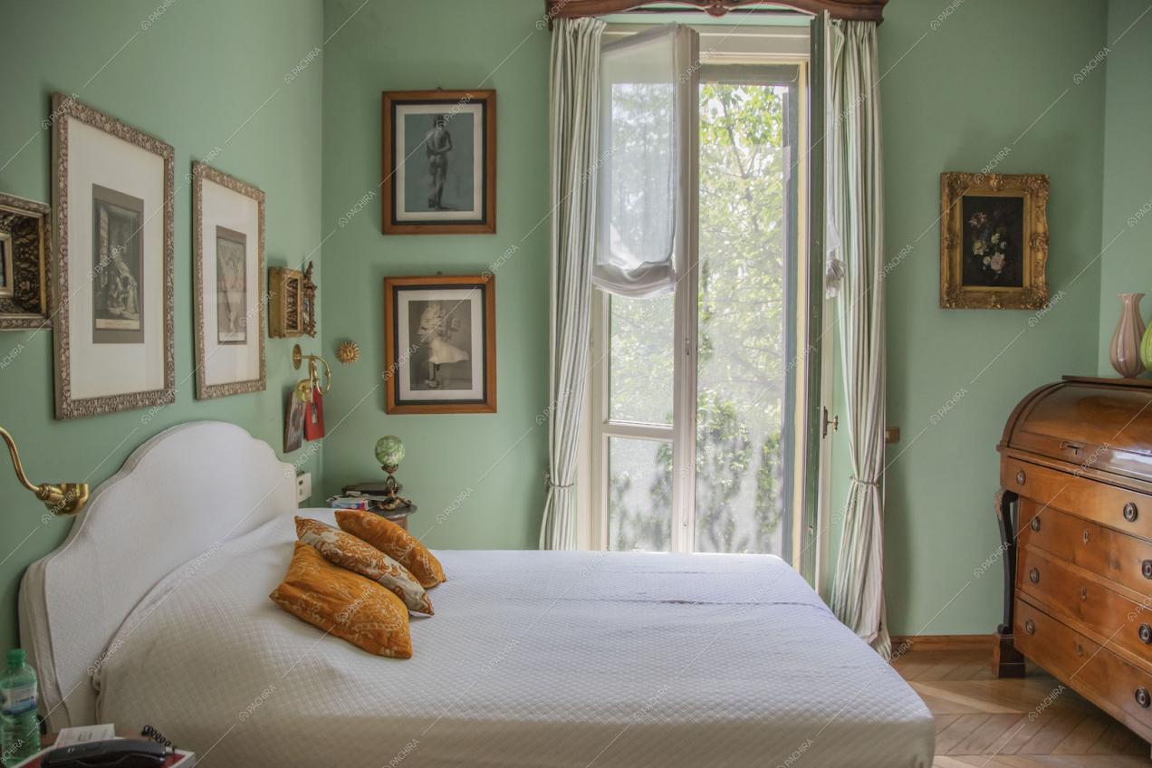 Luminosa camera da letto matrimoniale con pavimento in parquet e pareti verdi