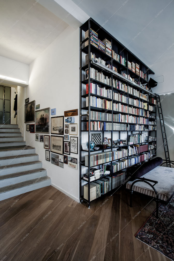 LIbreria a parete con scaletta nera, scale che portano al livello superiore