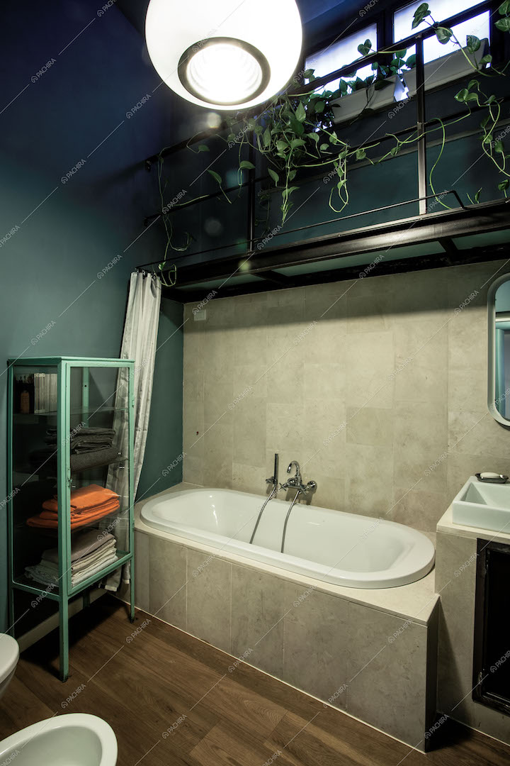 Bagno con vasca, armadietto in vetro e soppalco con rampicante