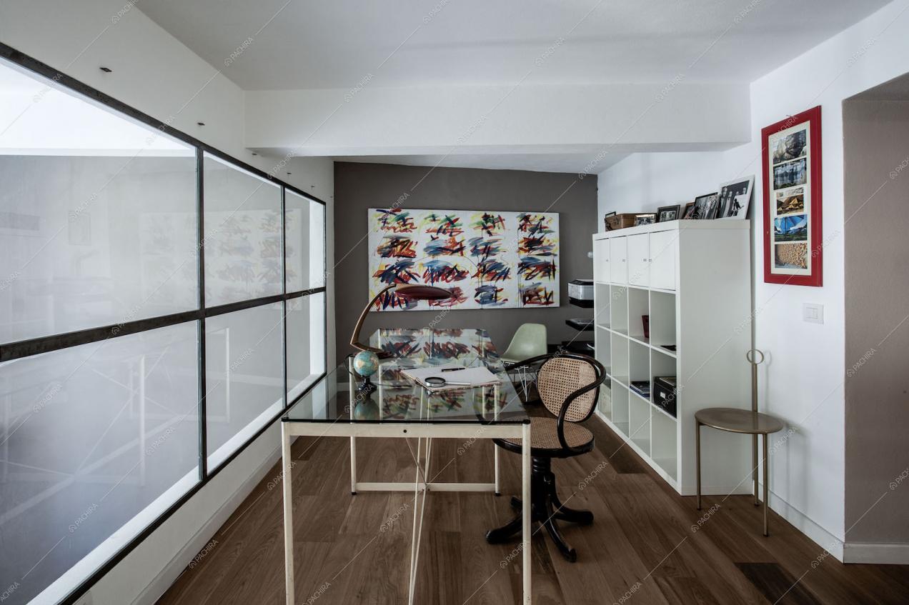 Studio sul soppalco con vetrata, tavolo in vetro e sedia di design