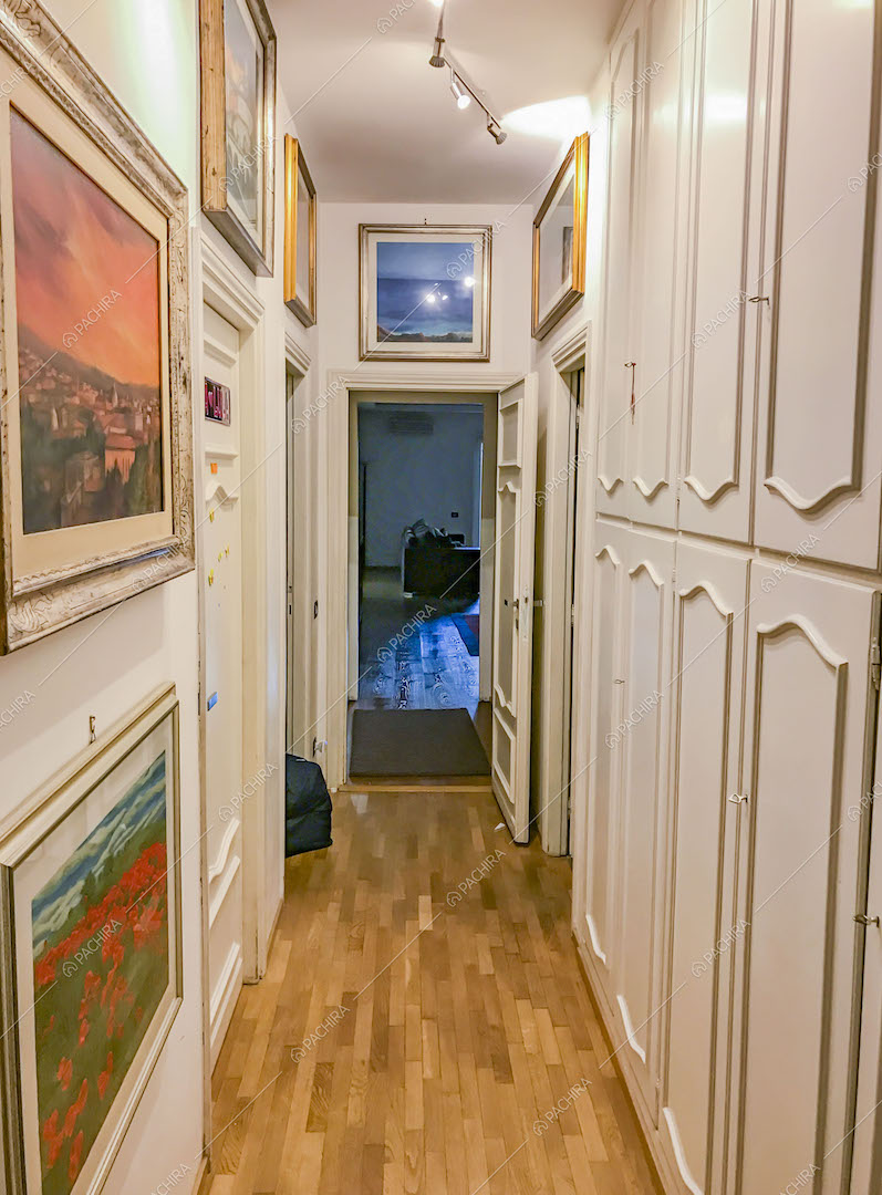 Corridoio con armadi bianchi e pavimento in parquet
