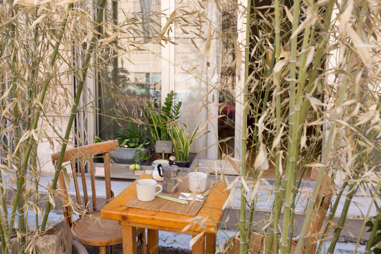 Piccolo tavolo da pranzo in legno, circondato da bambù
