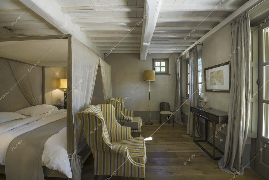 Camera con letto a baldacchino e travi a vista bianche