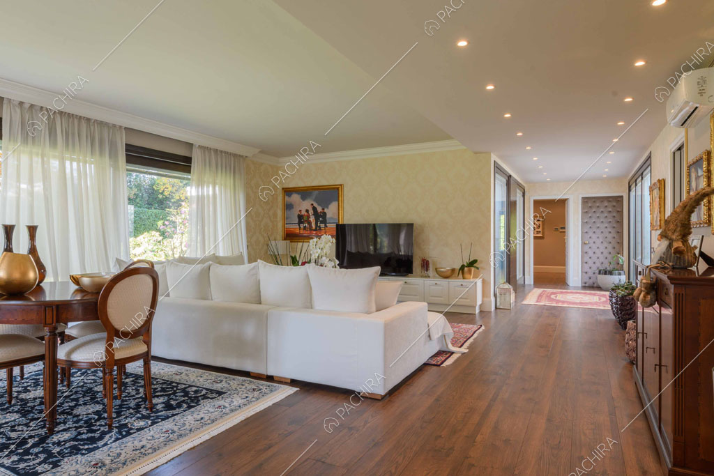 Carta da parati gialla nella zona living con pavimento in parquet e grandi vetrate