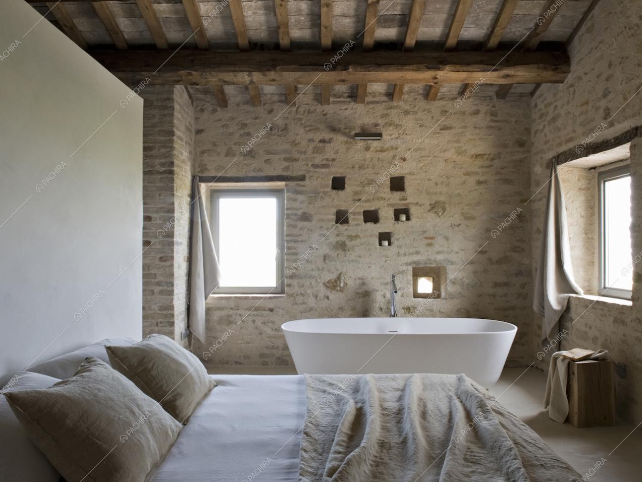 Camera da letto con travi a vista e pareti in mattoni