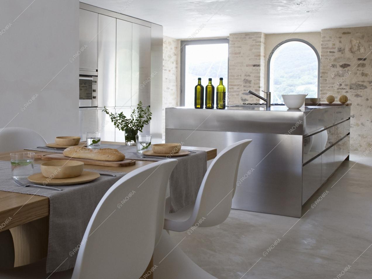 Il tavolo e la cucina a vista con dietro ampie vetrate
