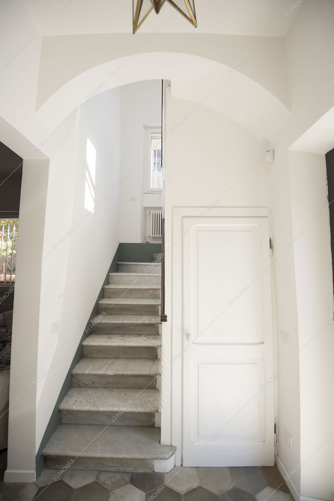 Scale in marmo, pavimento in cementine e porta bianca del bagno