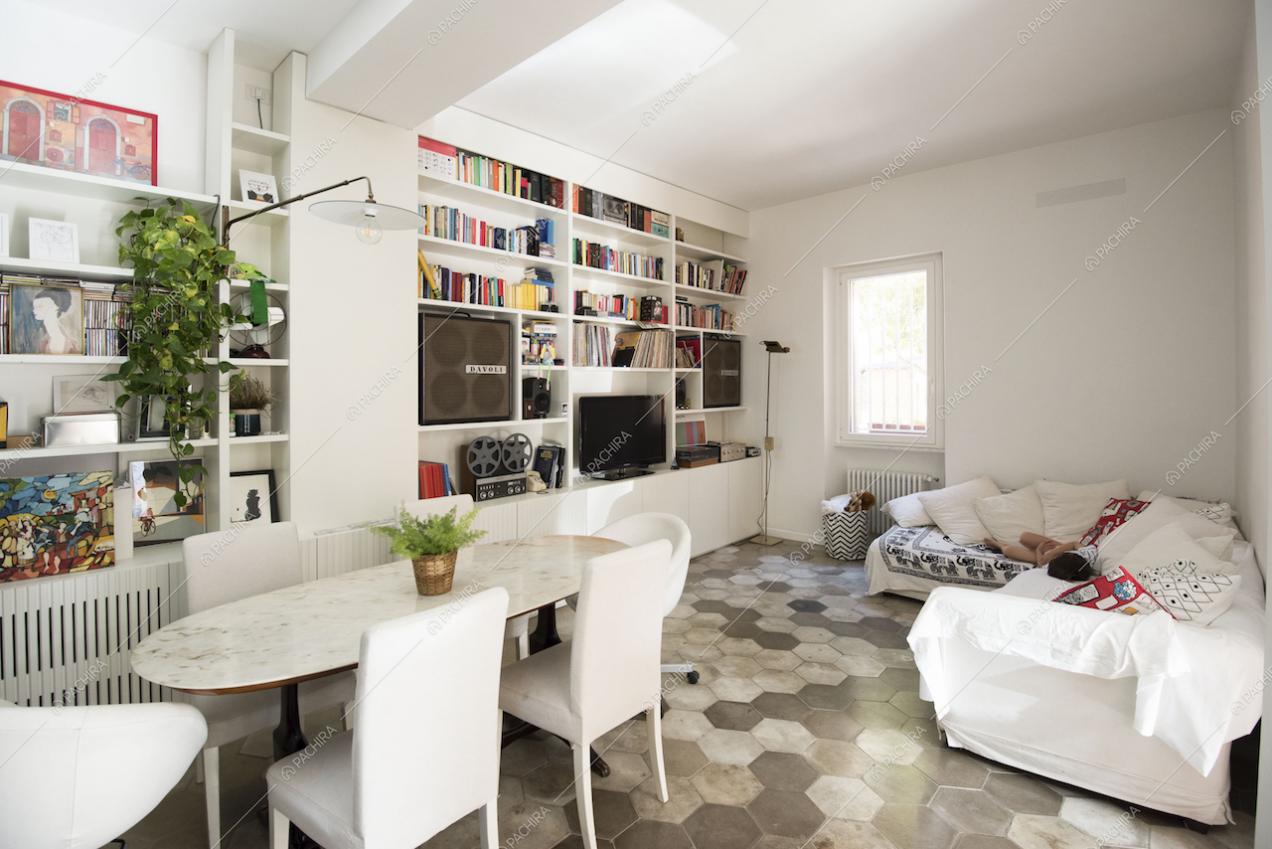 Zona living con divano bianco, televisore e pavimento in cementine