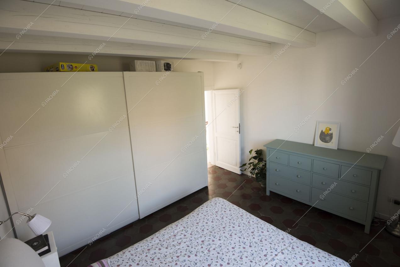 Camera da letto con grande cassettiera e travi bianche a vista