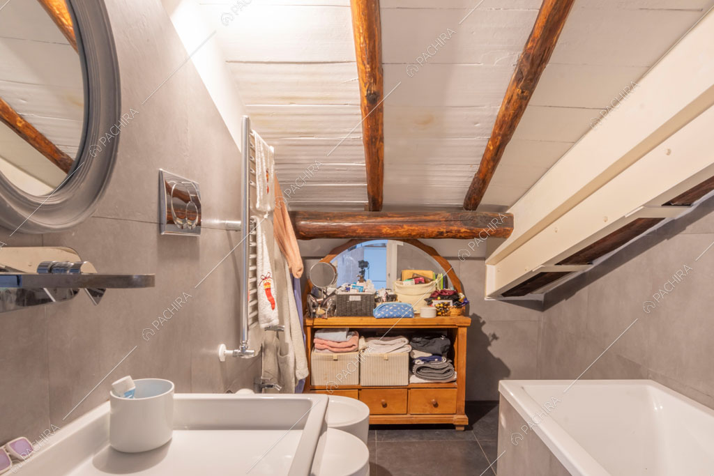 Bagno con travi in legno a vista sul soffitto nell'appartamento Uru, location in stile moderno a Roma