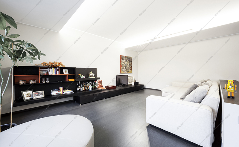 Zona living rialzata con divano bianco e libreria bassa nera