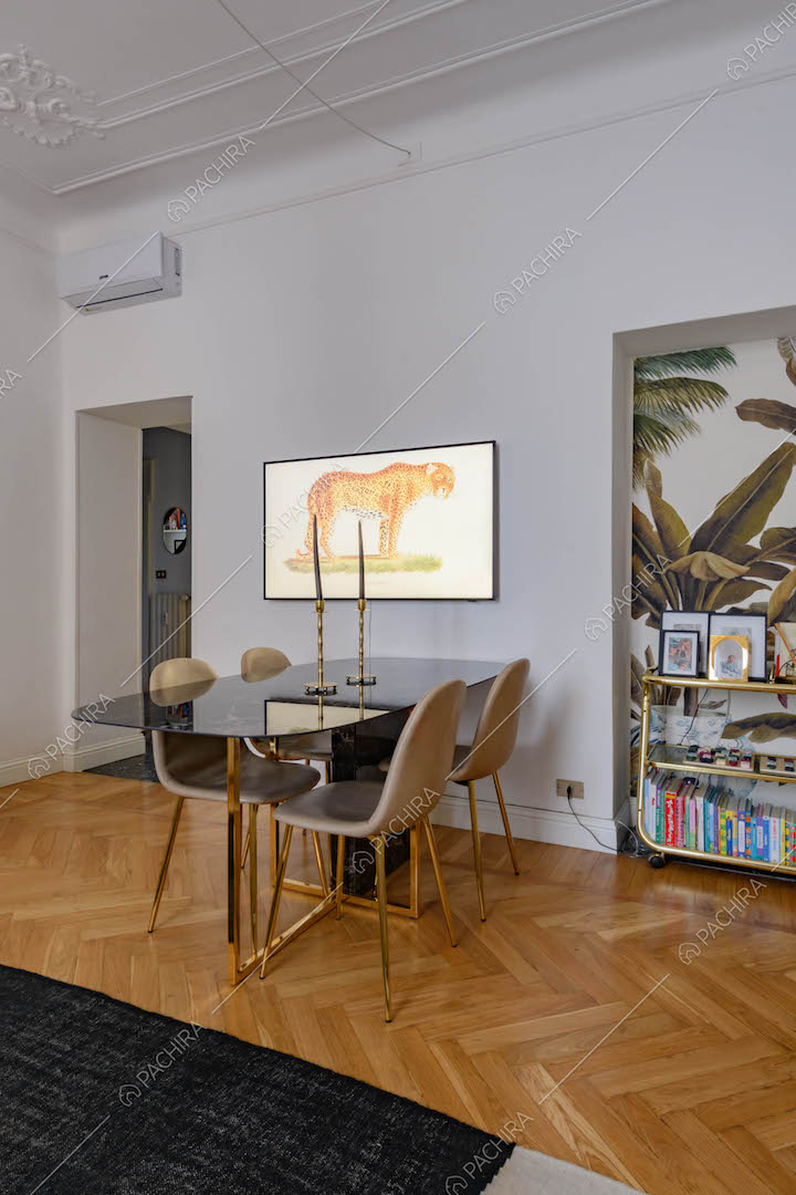Tavolo da pranzo di design nel grande salotto con boiserie sul soffitto e carta da parati