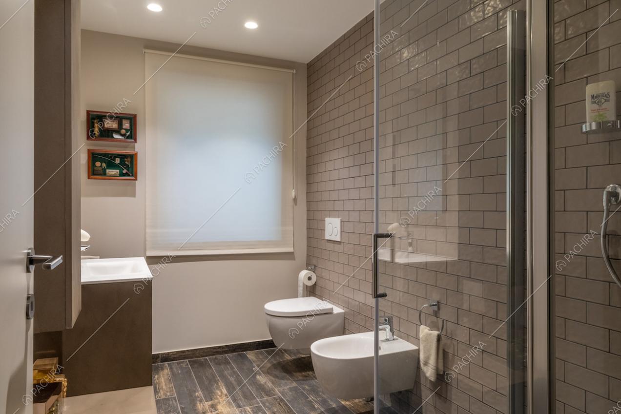 Bagno con pavimento in parquet, pareti in mattonelle e box doccia