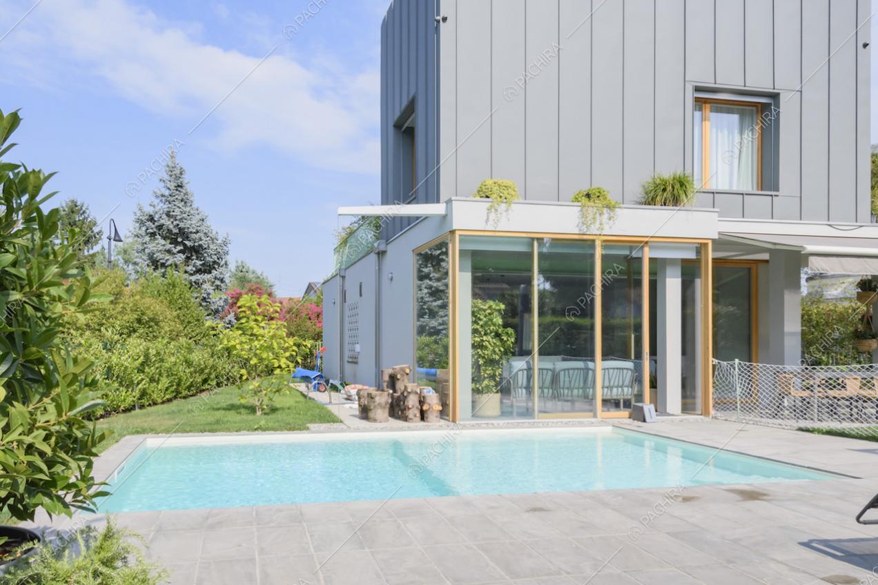Facciata della villa con ampie vetrate e piscina esterna