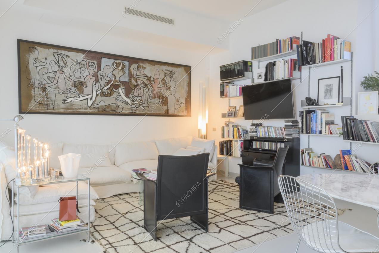 Salotto con divano bianco, poltroncine nere e libreria