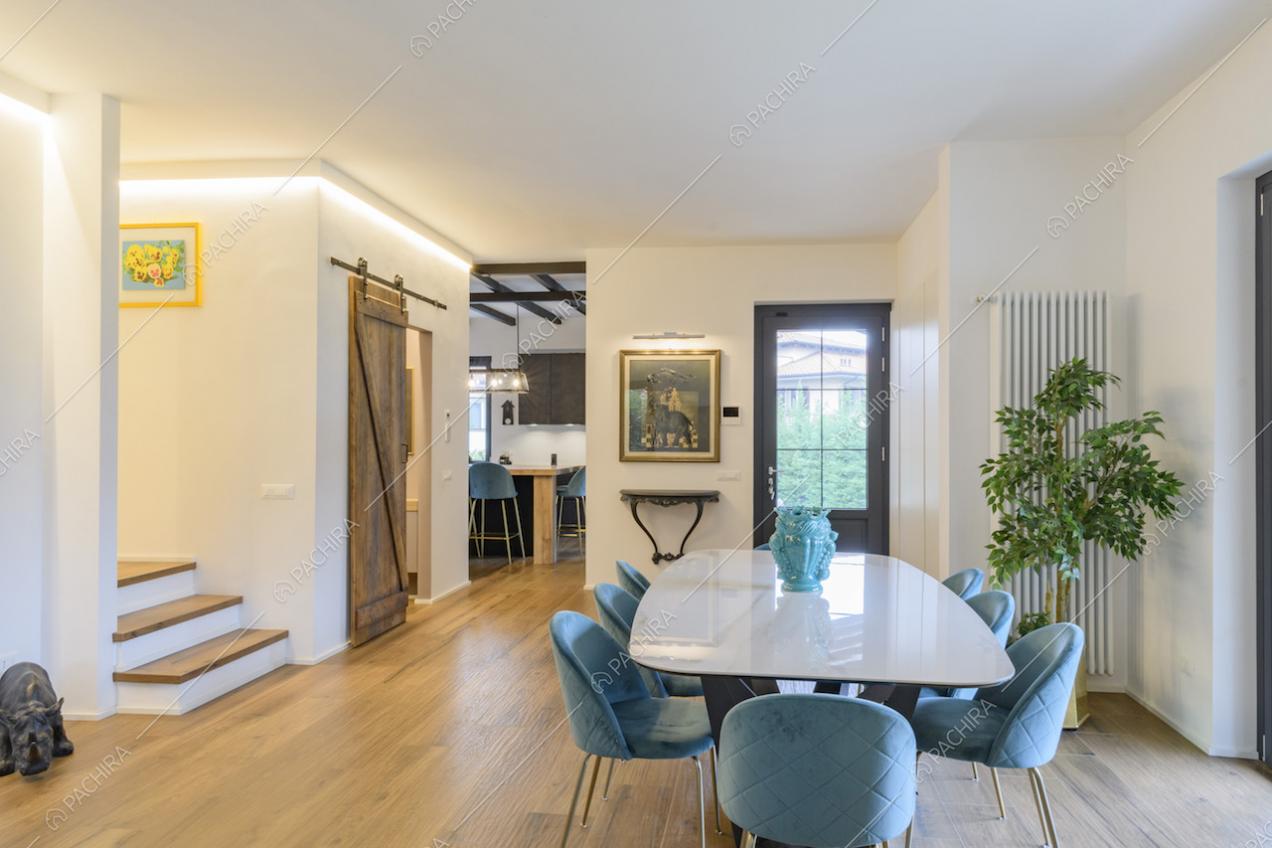 Zona pranzo con tavolo bianco e sedie in velluto azzurro