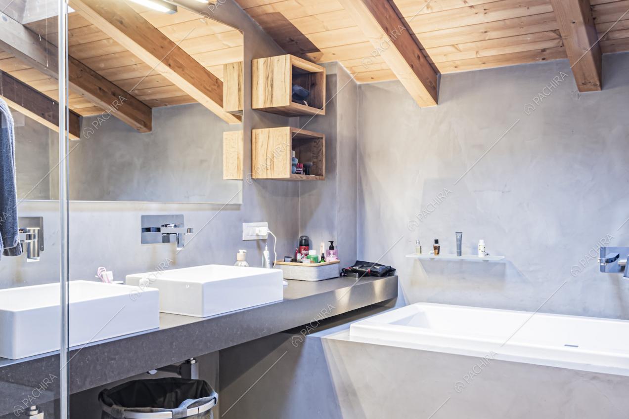 Vasca da bagno, lavandini moderni, specchio e travi in legno