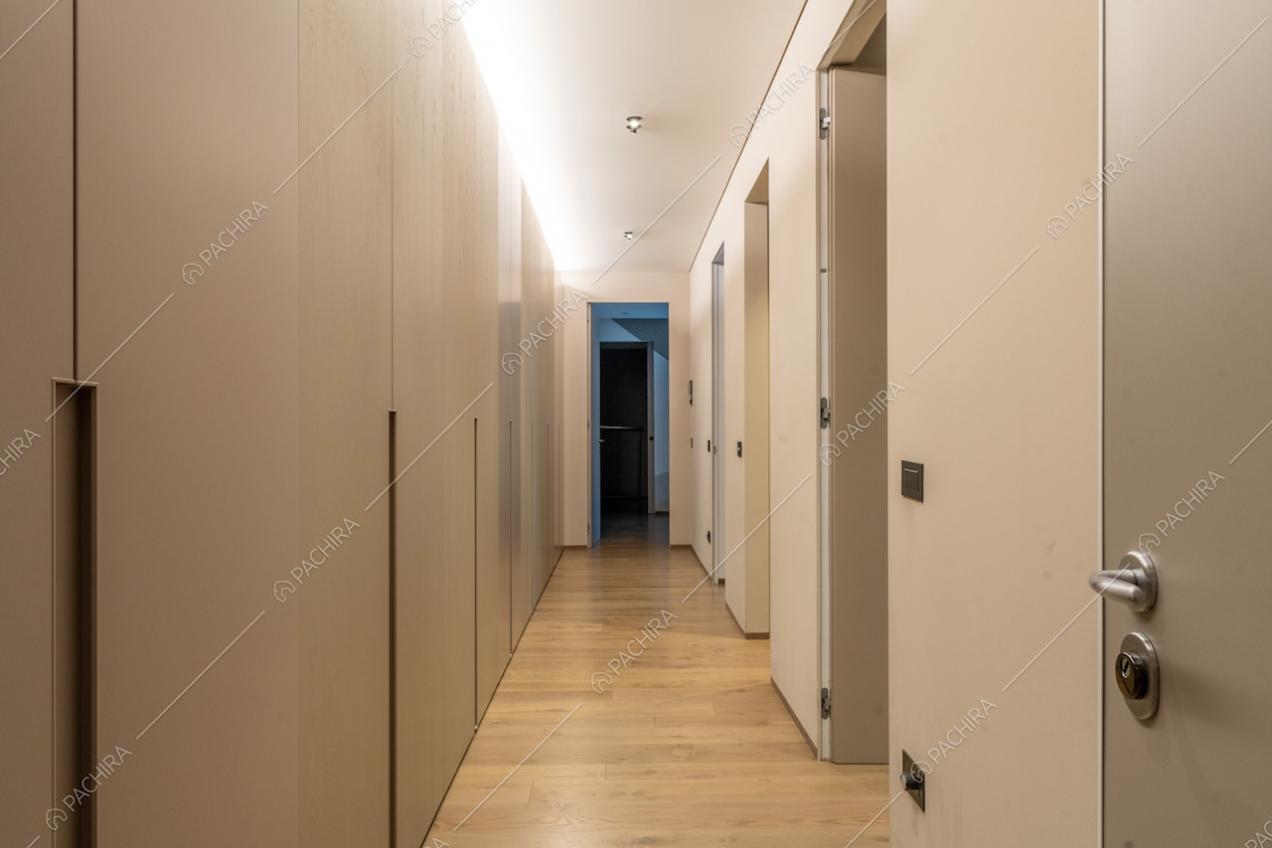 Lungo corridoio con pavimento in parquet e armadi a parete
