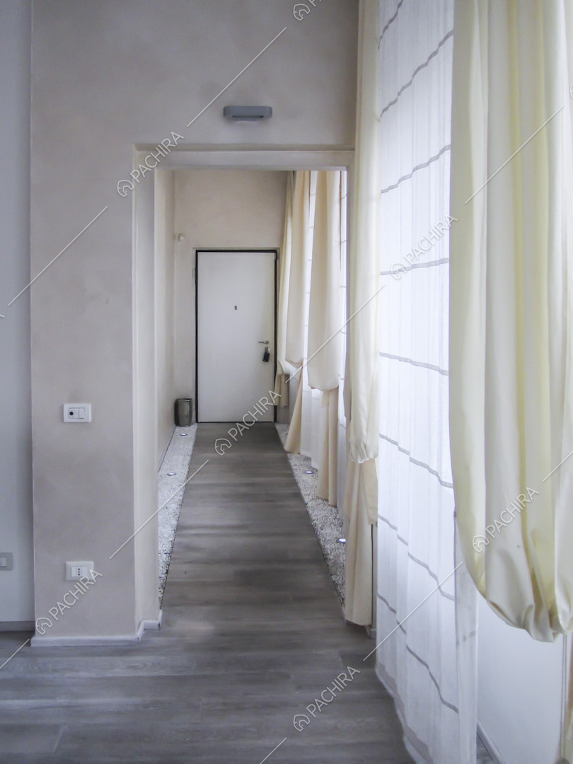 Porta d'ingresso e corridoio con ai lati sassolini e faretti