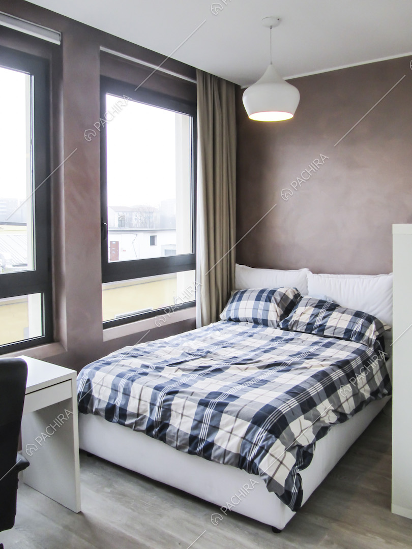 Letto a due piazze, lampadario bianco e pavimento in parquet