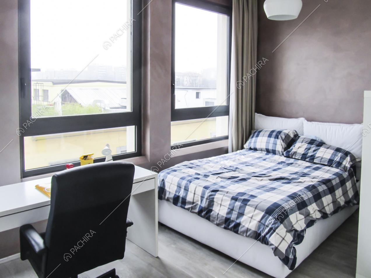 Camera da letto con scrivania, poltrona nera girevole e ampie vetrate
