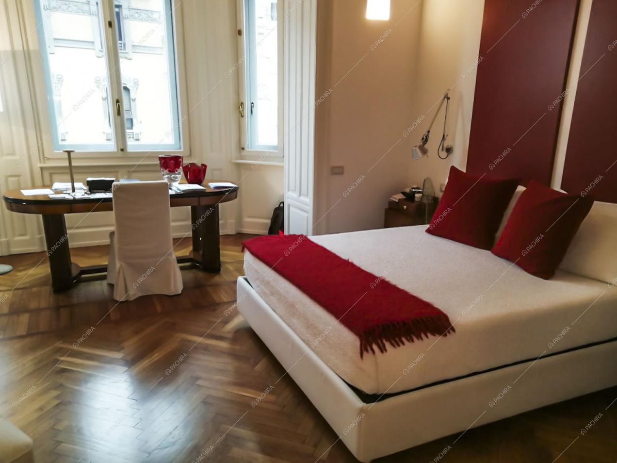 Pavimento in parquet a spina di pesce in camera da letto matrimoniale con scrivania e pareti bianche con boiserie