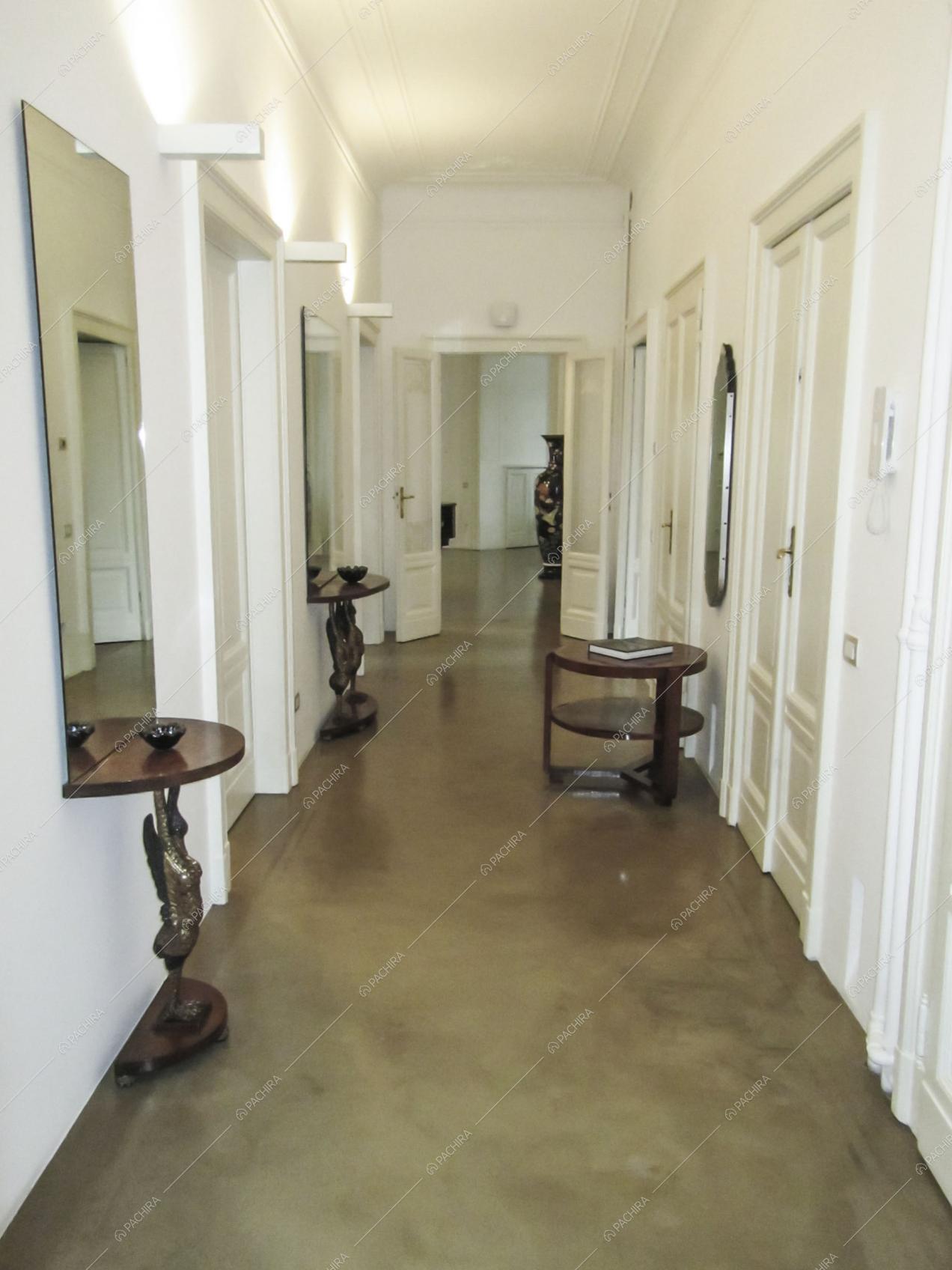 Ampio corridoio con soffitto bianco con boiserie e tavolini in legno