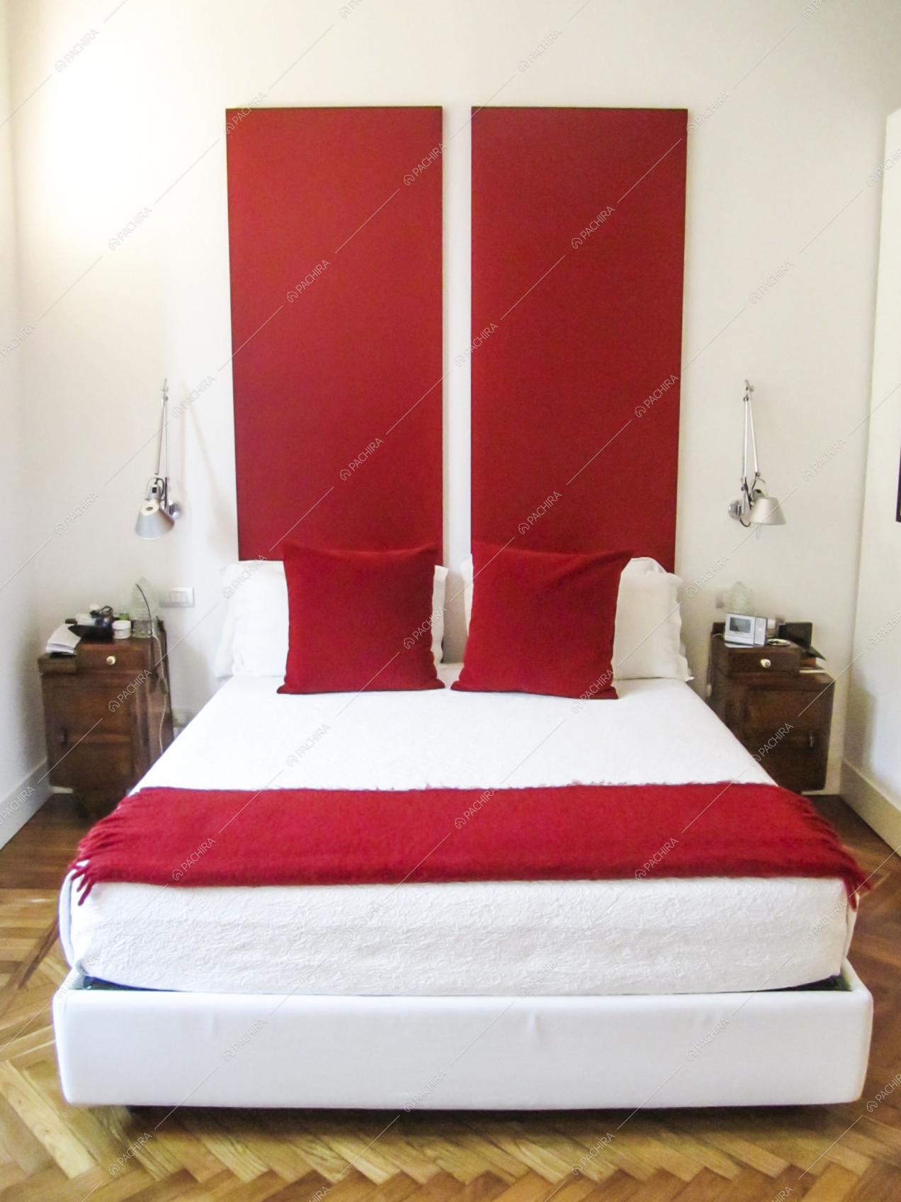 Letto matrimoniale bianco in luminosa camera con pavimento in parquet a spina di pesce