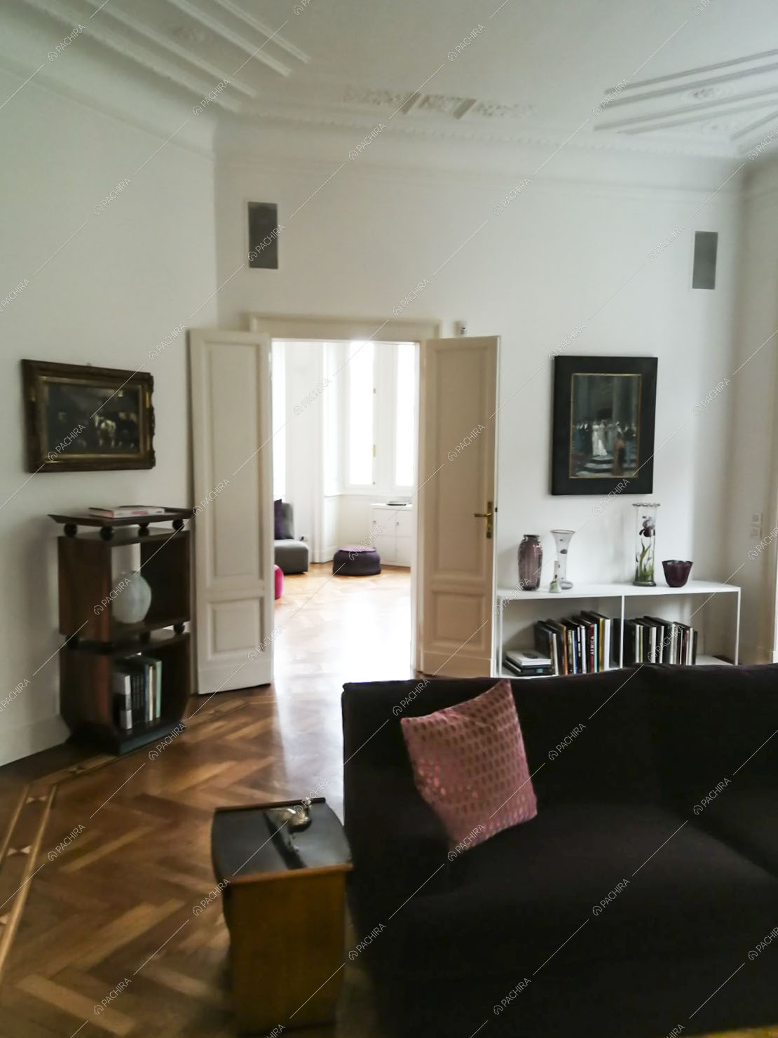 Soggiorno con divano viola, pareti bianche, soffitto con boiserie e pavimento in parquet a spina di pesce