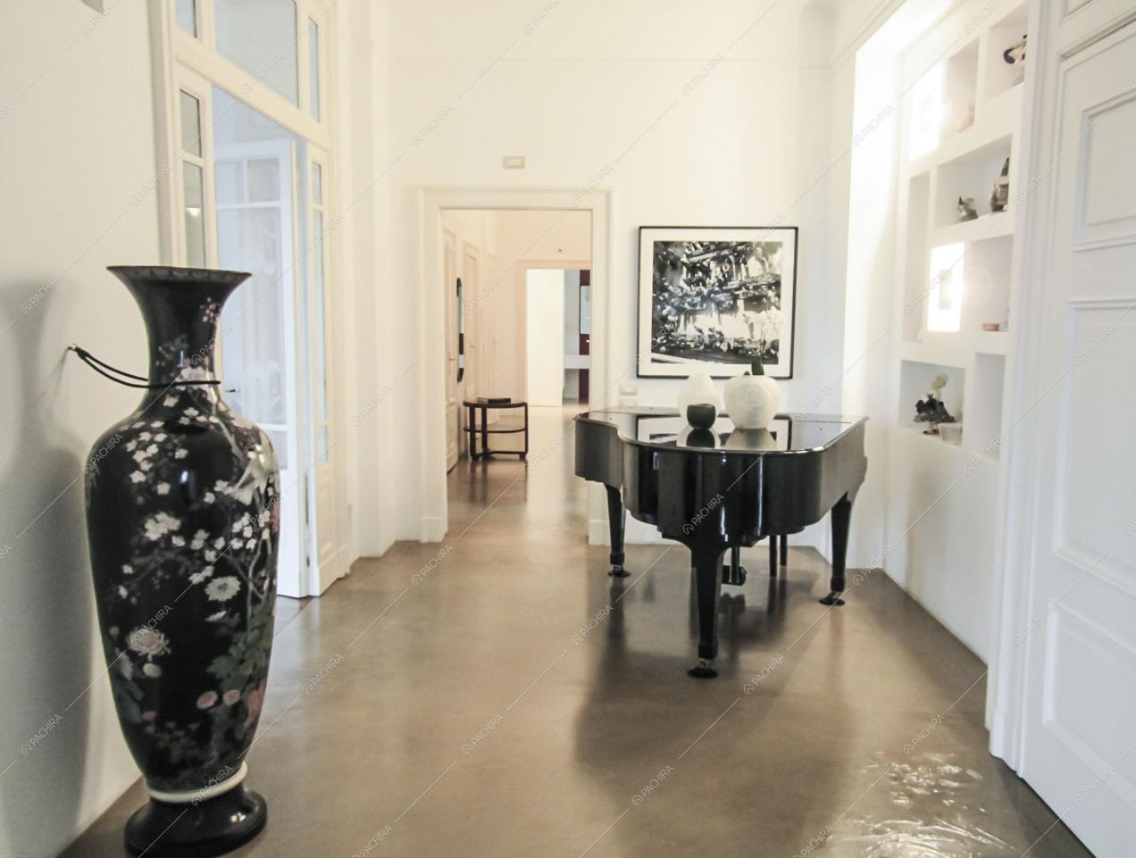 Pavimento grigio in resina in corridoio dalle pareti bianche con pianoforte