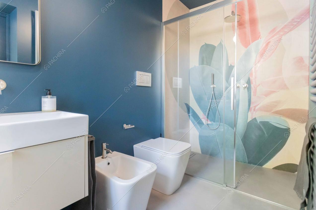 Bagno con box-doccia, dalle pareti blu e con carta da parati a fantasia floreale