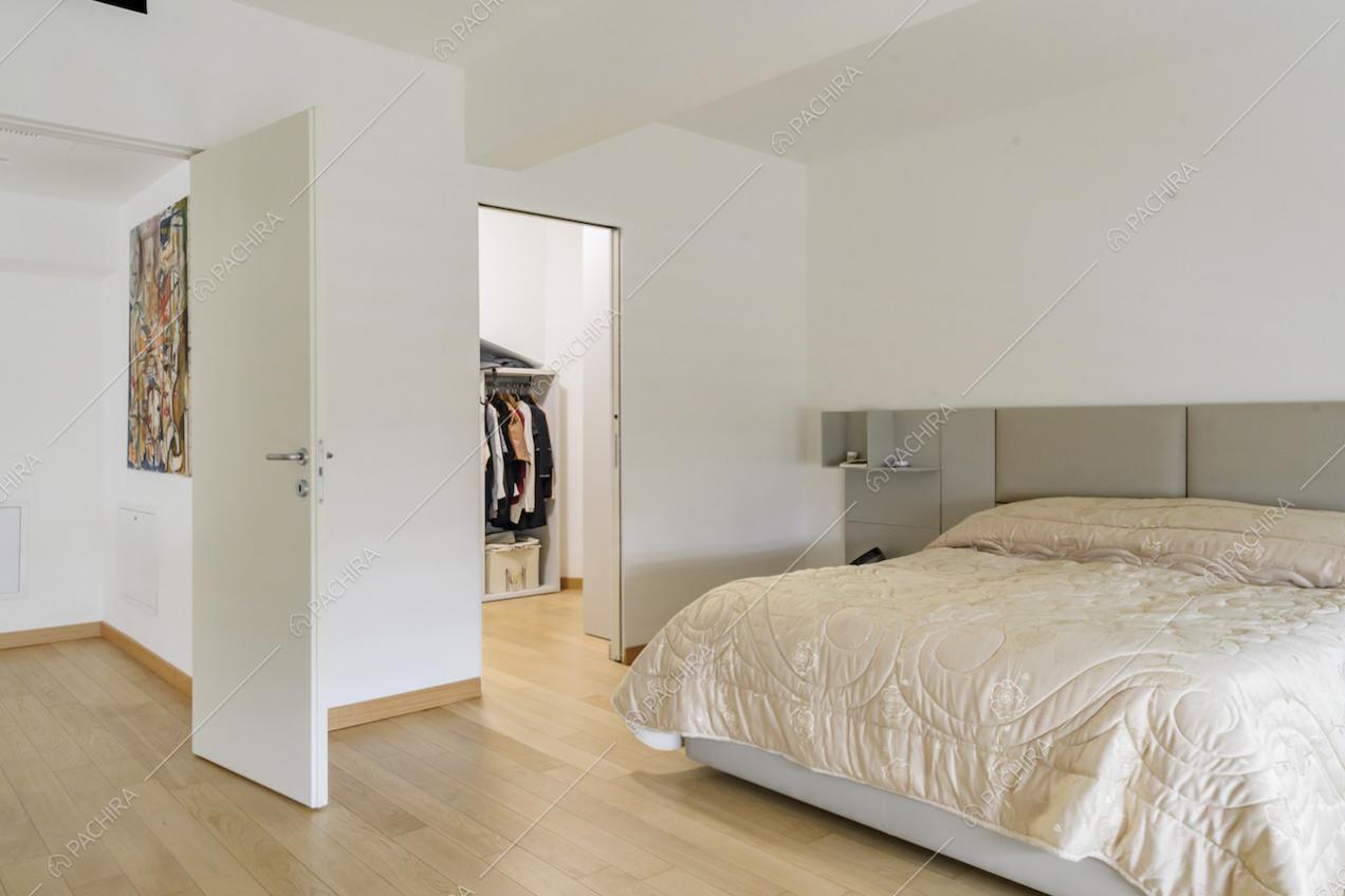 Camera da letto minimal con pavimento in parquet, pareti bianche e cabina armadio