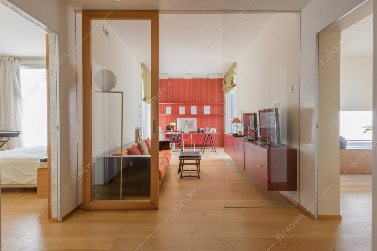 Studio con divano, scrivania, porte a vetri e pavimento in parquet