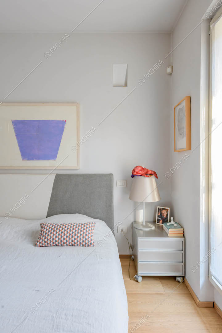 Camera da letto matrimoniale con grande finestra e pavimento in parquet