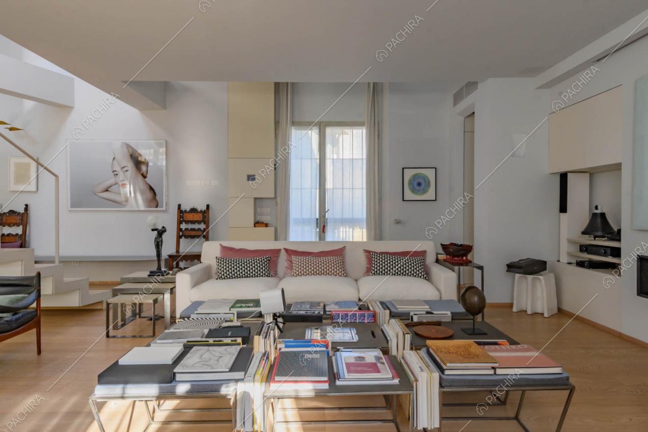 Tavolino di design nel salotto con divani bianchi, camino e pavimento in parquet