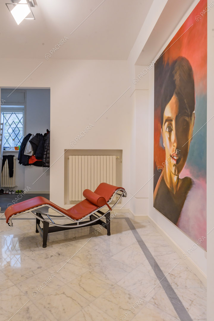 Pavimento in marmo bianco nell'atrio con chaise longue rossa