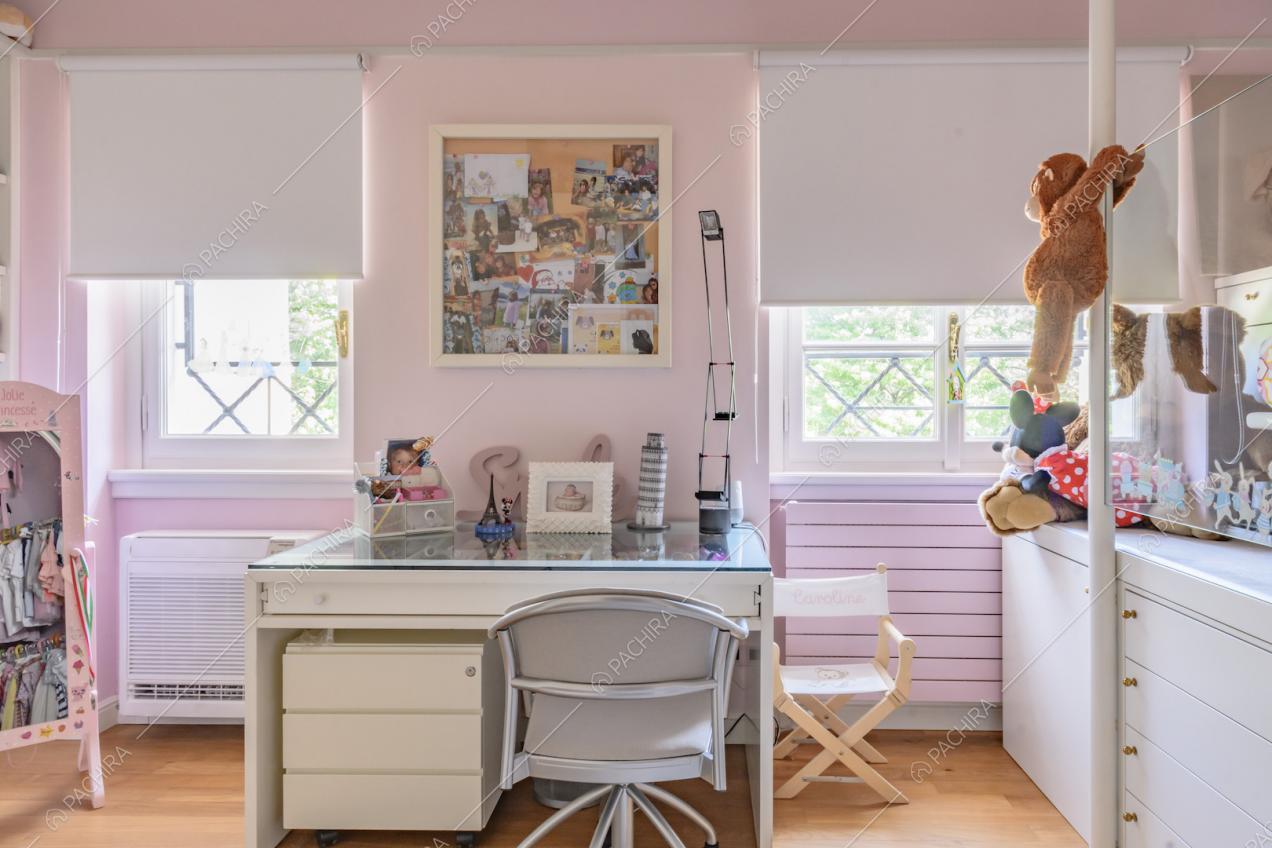 Scrivania nella camera dei bambini con pavimento in parquet, pareti rosa e letto rialzato