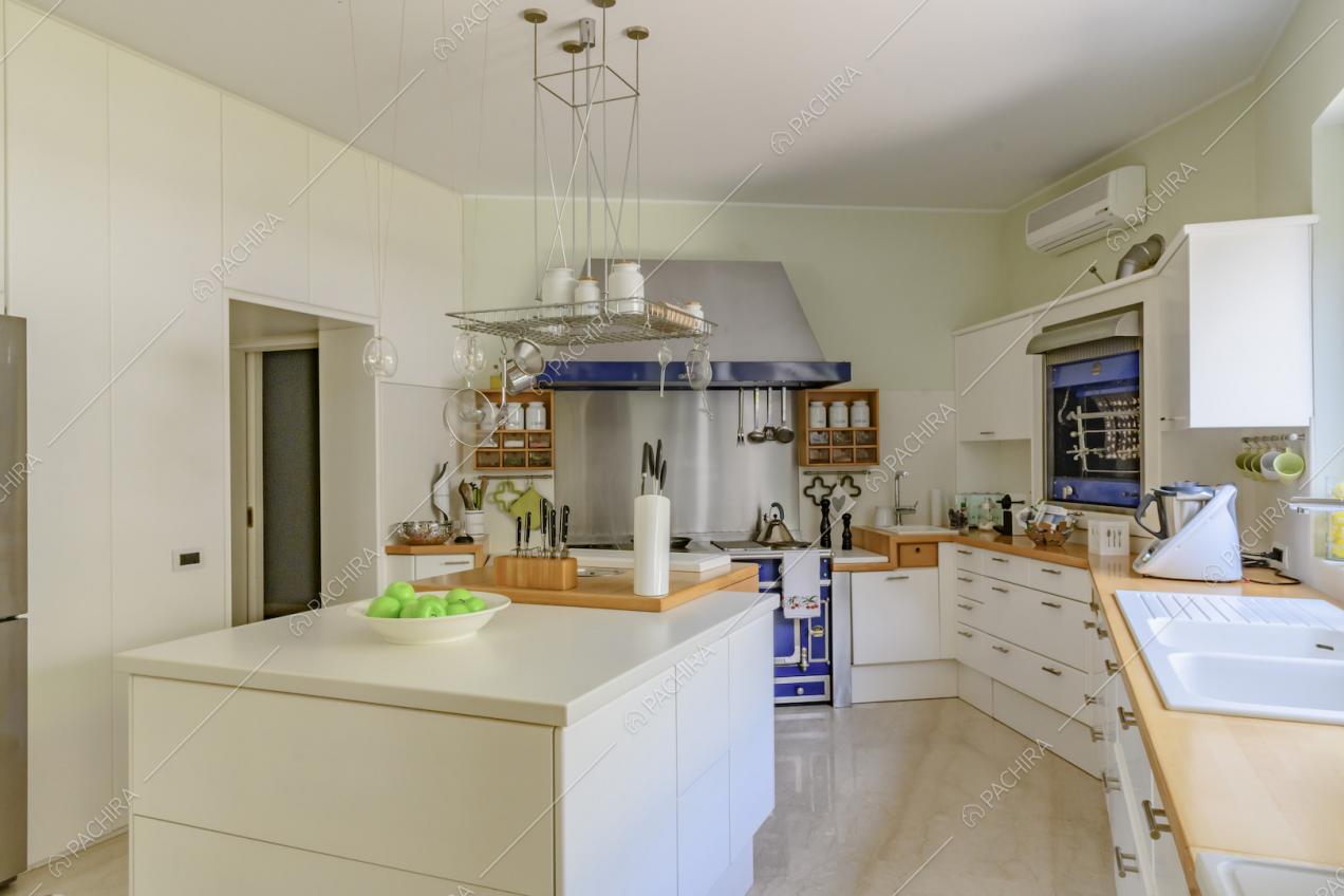 Luminosa cucina con isola bianca, pavimento in marmo e pareti verde chiaro