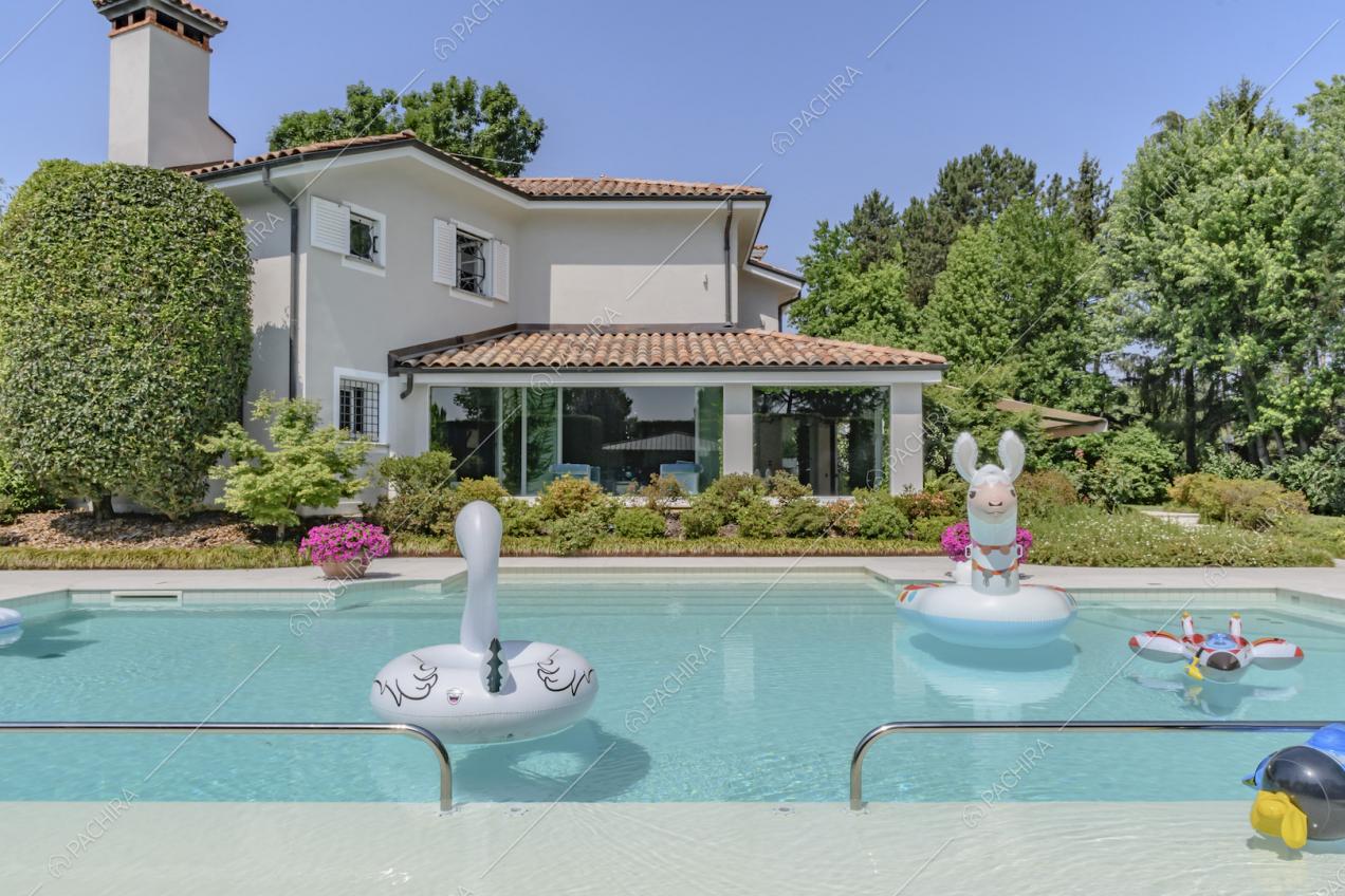 Piscina con gonfiabili e vista sulla veranda con grandi vetrate della villa
