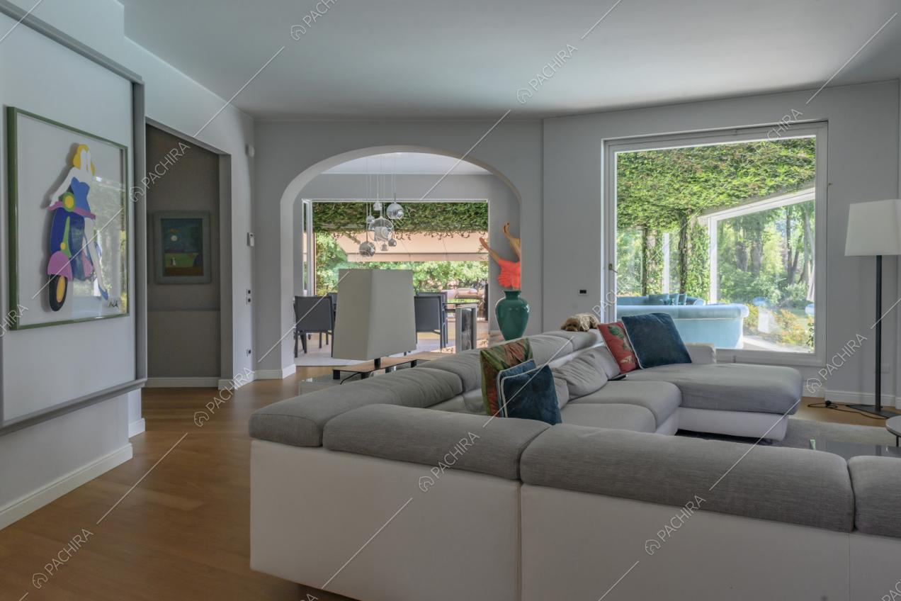 Divano angolare grigio e bianco nel salotto con pavimento in parquet e vista tramite l'arco a volta sulla sala da pranzo