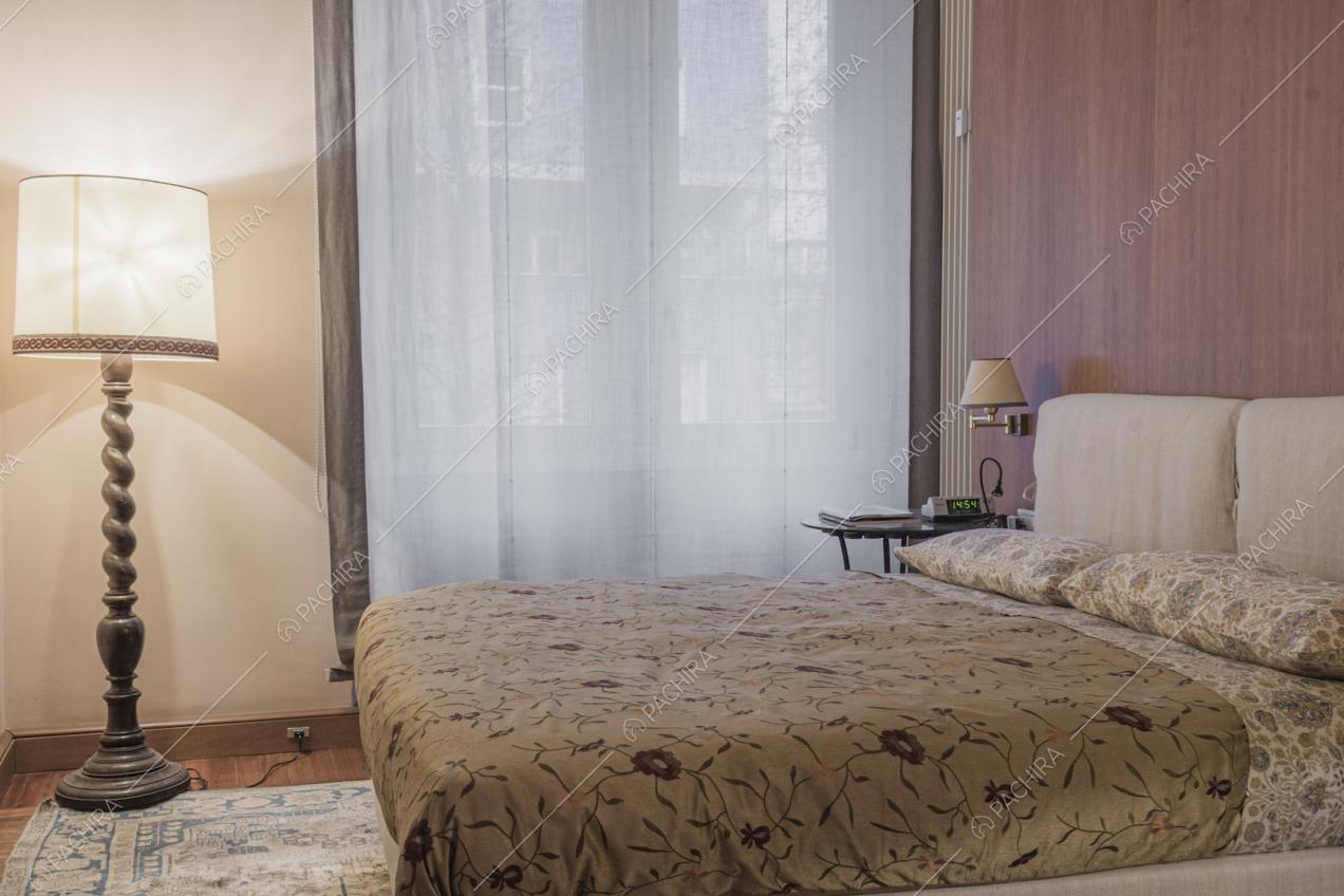 Letto matrimoniale e lampada da terra con gamba in legno