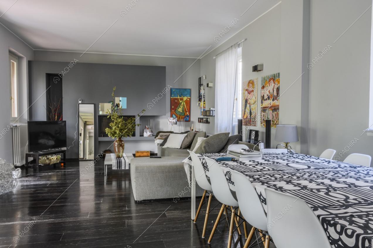 Tavolo da pranzo con sedie bianche di design, pareti grigie e parquet nero