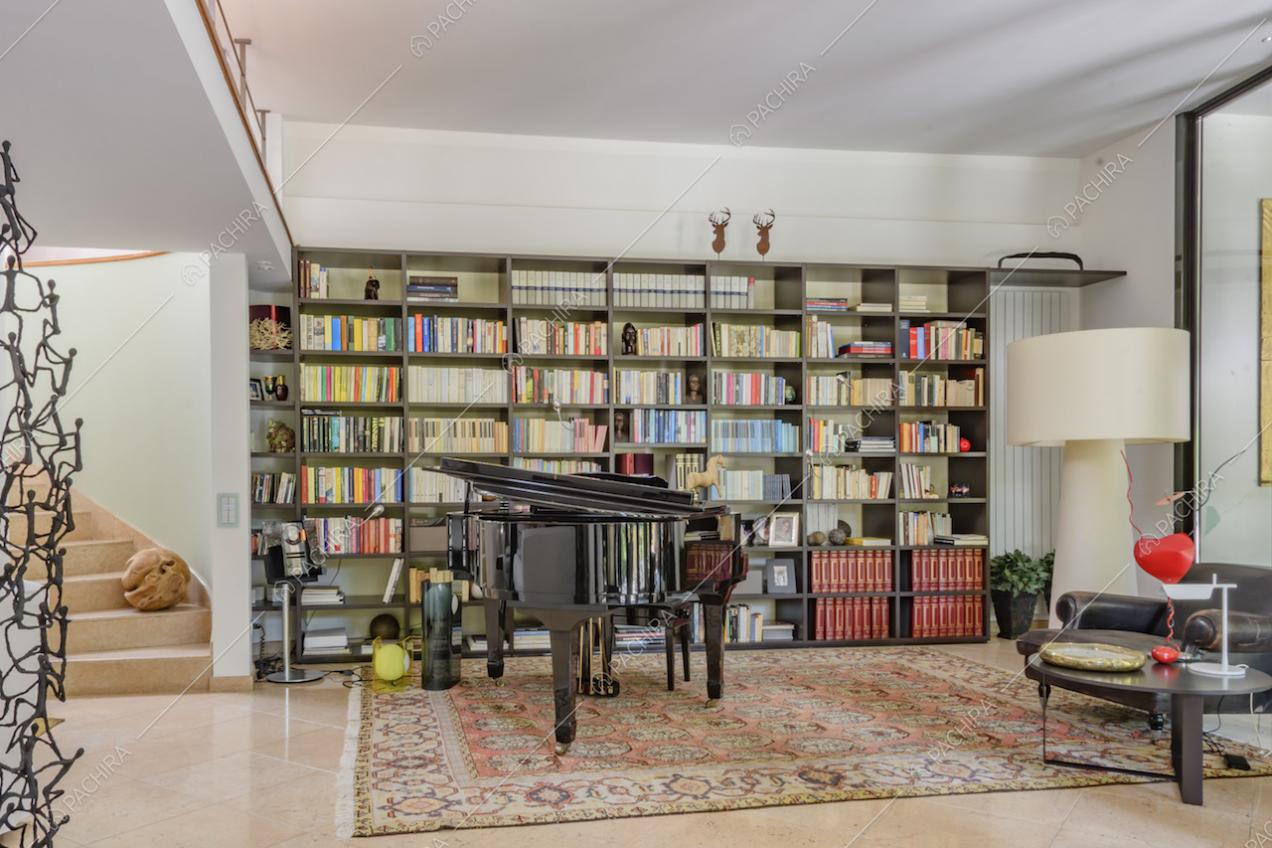 Grande libreria lungo la parete e pianoforte a coda nero