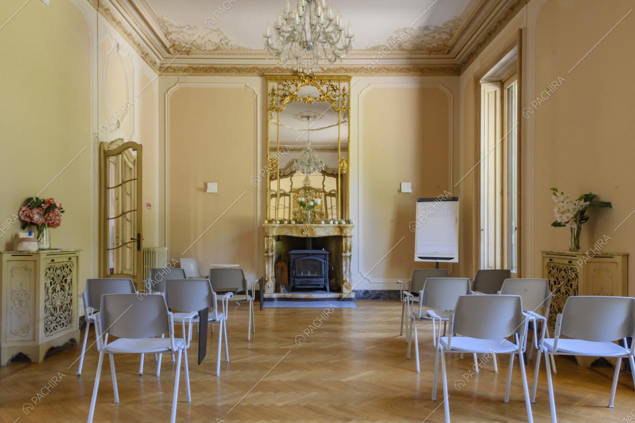 Luminoso salone con boiserie su soffitto e pareti, camino e maestoso specchio incastonato in una cornice dorata