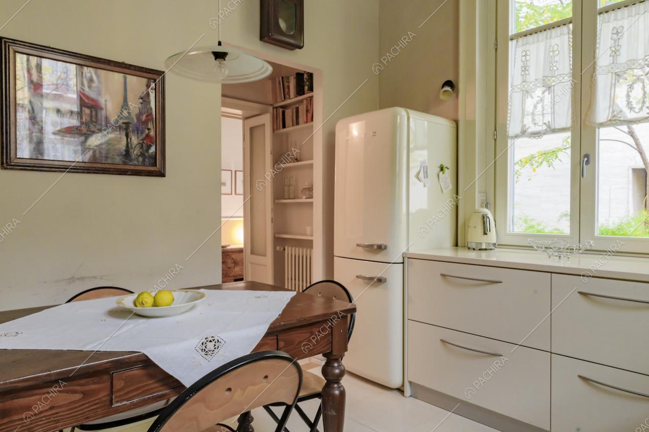 Luminosa cucina bianca a parete con tavolo da pranzo in legno