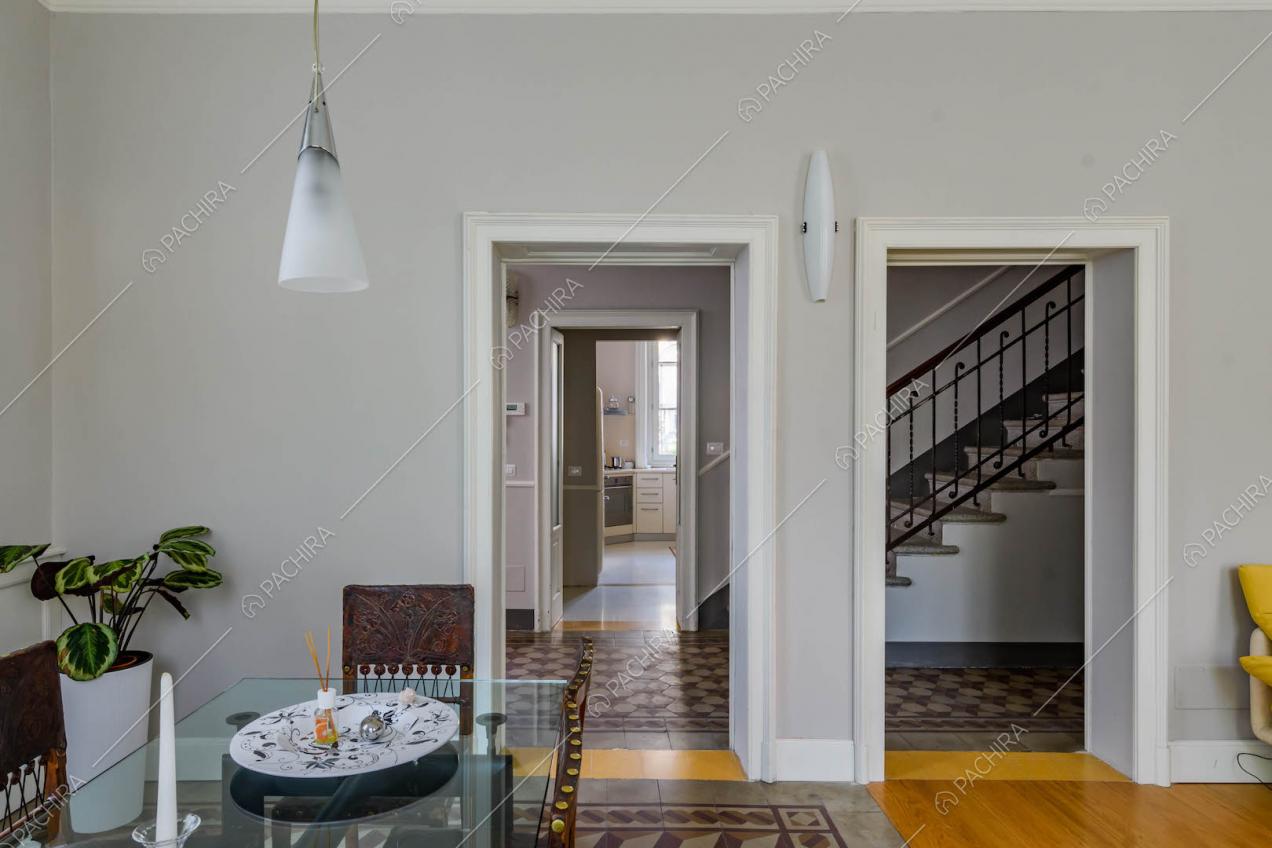 Dal tavolo da pranzo nella sala con pareti grigie vista sulle scale e sulla cucina a parete