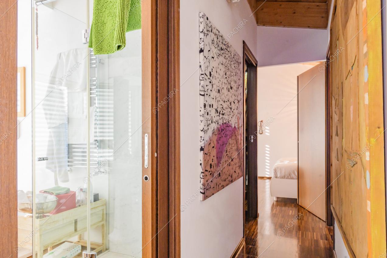 Corridoio con quadri moderni appesi alle pareti e scorcio sul bagno