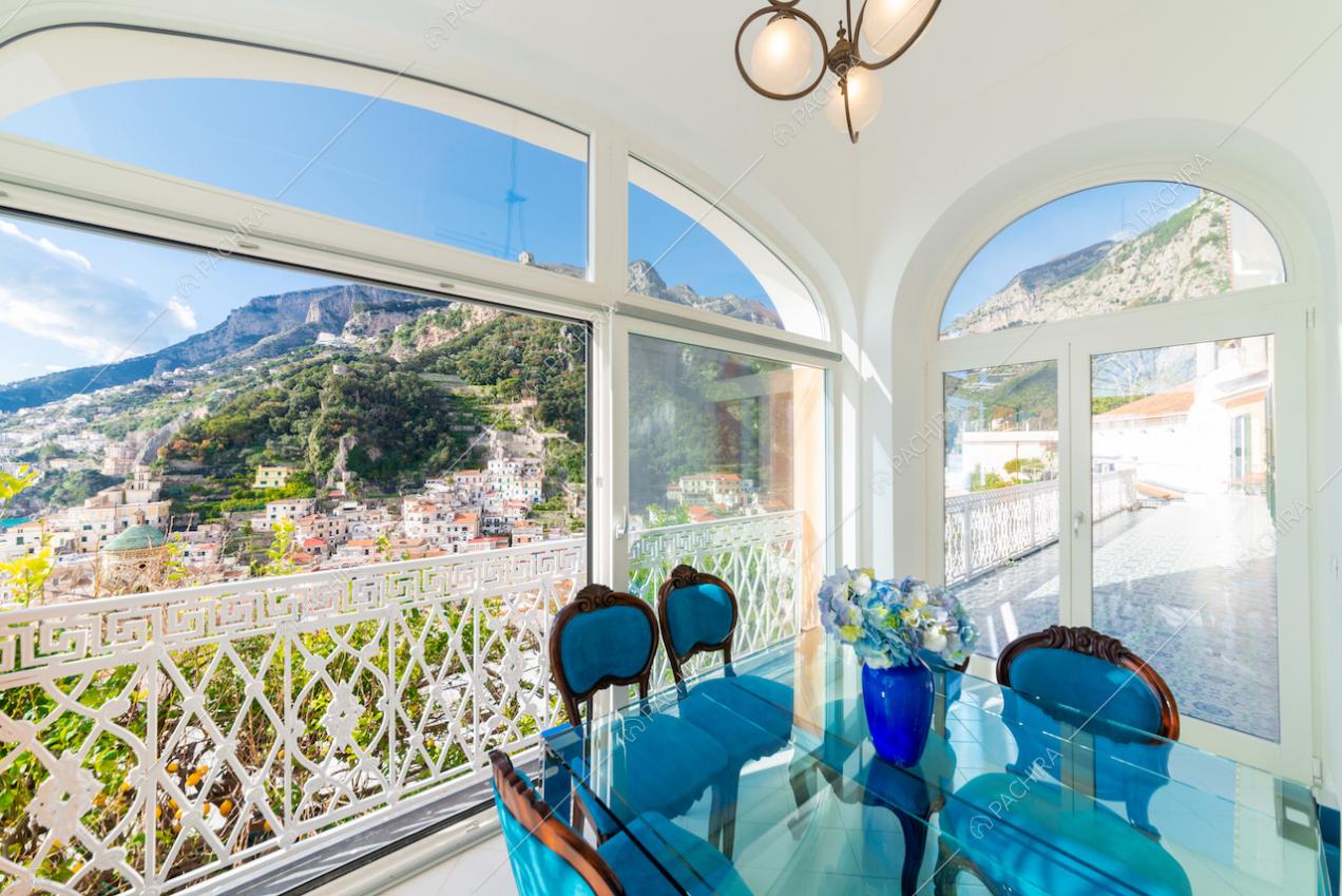 Zona pranzo circondata da vetrate e ringhiera bianca decorata