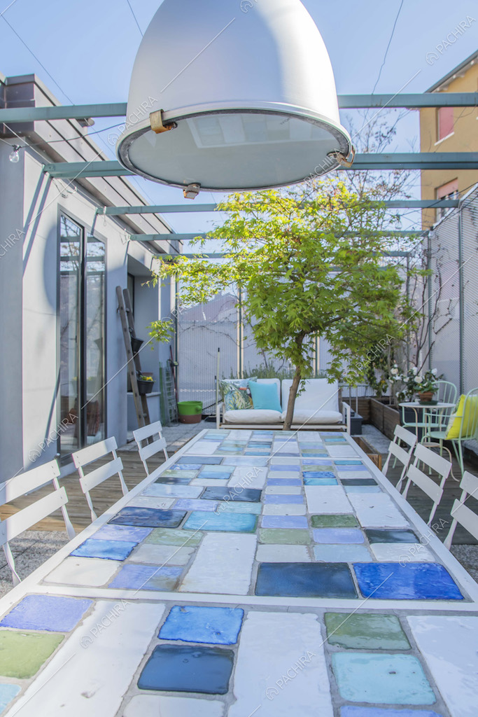 Tavolo con piastrelle e lampadario nella terrazza con divano da esterni